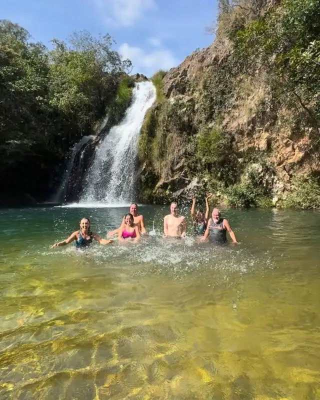 Visitantes tomando banho no poço de uma cachoeira