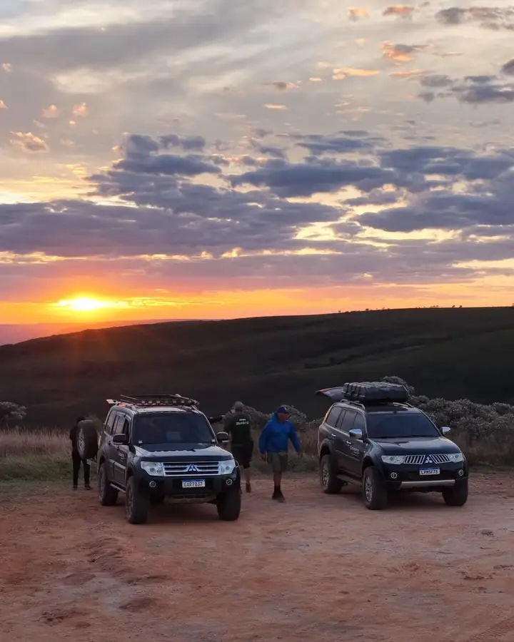 Duas caminhonetes da agência no alto da serra ao pôr do sol