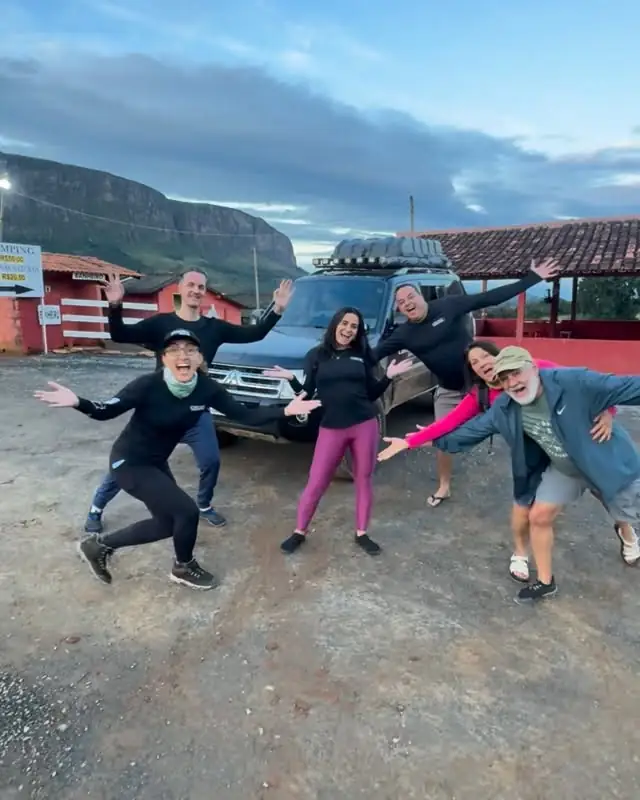 Grupo de visitantes comemorando ao lado de uma caminhonete da agência